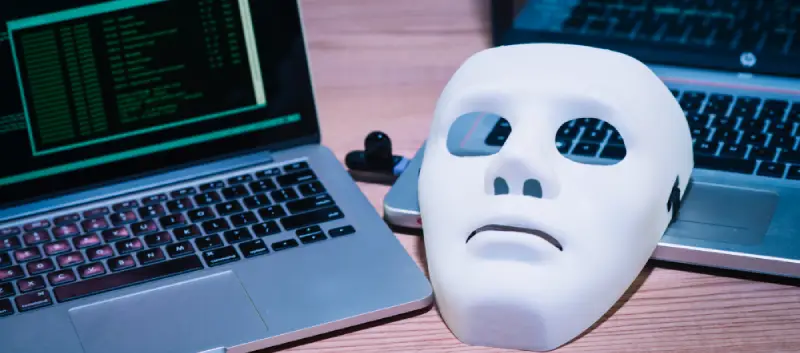 Migrinfo - Protection contre les cybermenaces Deux ordinateurs avec un masque symbolisant la sécurité informatique