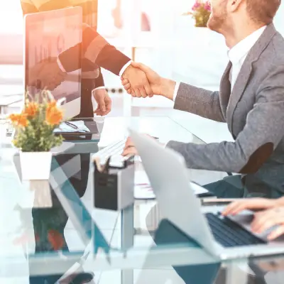 Migrinfo - Satisfaction client au cœur de nos priorités Deux personnes se serrant la main symbolisant la satisfaction client